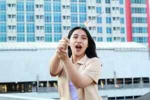 beautiful asian young woman holding sparklers firework and laughing in new year eve celebration standing in roof top outdoor with urban building background photo