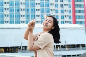 beautiful asian young woman holding sparklers firework and laughing in new year eve celebration standing in roof top outdoor with urban building background photo