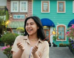 happy young asian woman holding sparkler celebrating new year eve in vintage house yard, outdoor garden photo