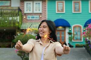 happy young asian woman holding sparkler celebrating new year eve in vintage house yard, outdoor garden photo