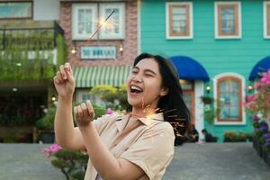 happy young asian woman holding sparkler celebrating new year eve in vintage house yard, outdoor garden photo