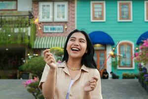 happy young asian woman holding sparkler celebrating new year eve in vintage house yard, outdoor garden photo