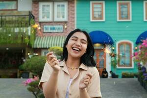 happy young asian woman holding sparkler celebrating new year eve in vintage house yard, outdoor garden photo