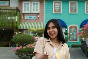 portrait of beautiful happy young asian woman holding sparklers fireworks to celebrate new year eve with garden party standing in outdoor vintage house yard photo