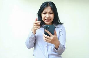 beautiful asian young woman angry using mobile phone pointing with forefinger to screen wear formal suit isolated on white background photo