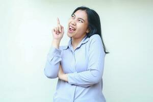 excited asian young business woman pointing up with arm folded and looking above dressed in formal suit, female isolated on white background photo