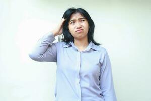 confused asian woman looking above with curiosity touching her head dressed in formal suit isolated in white background photo