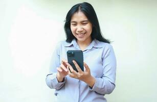 charming asian young business woman using mobile phone app, chatting and online shopping, looking screen surfing in sosial media and read good news, wearing formal shirt standing over white background photo