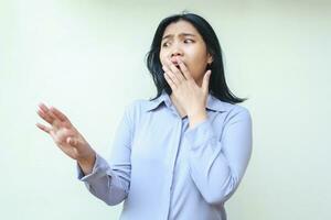 shocked beautiful asian young business woman looking away frightened with hands reaching out and covering her open mouth wearing formal office clothes standing over isolated white background photo