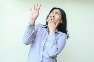shocked asian young pretty business woman scared looking up, covering open mouth and raising arm, wearing formal shirt standing over isolated white background photo