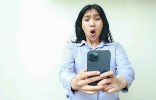 amazed asian young business woman using smartphone shocked with wow expression wearing formal shirt standing over isolated white background photo