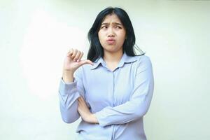 confused asian young business woman giving thumbs down looking aside with folded arm show upset expression felling dissatisfied wearing formal shirt standing over isolated white background photo