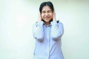 depressed asian young business woman covering ears and head with closed eye, overwork female stressed wearing formal purple shirt standing isolated over white background photo