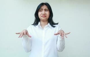 portrait of doubtful asian woman office girl wearing white formal suit shirt raising palms standing do uderestimate gesture showing do not believe expression looking away photo