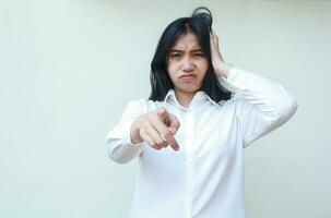 image of overworked stress asian woman office employee pointing and looking at camera with hands push her dark hair wearing white formal shirt, displeased expression feeling crazy, standing photo