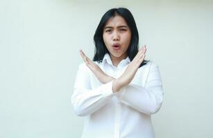 portrait of angry asian business woman crossed arm gesture showing rejection sign and screaming no to camera with afraid and scared expression wear white formal suit standing over isolated background photo