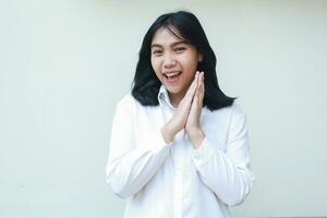 playful succes asian young business woman stick palms together wearing white suit formal shirt, confident looking at camera with excitement face expression, standing over isolated background photo