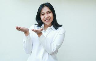 confident asian young business woman secretary rasing arms show open palm looking camera with toothy smile wearing white formal shirt, excited introduce imaginary product, isolated on white background photo