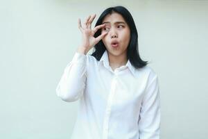 thoughtful asian young woman looking away daydream, surprised open her eye with fingers showing wow expression, wearing white formal suit shirt isolated photo