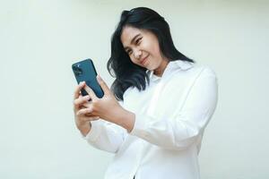 elagance asian business woman with gratitude using smartphone to take selfie and video call online communication wearing white suit shirt, surfing in social media cyberspace, read good news, standing photo