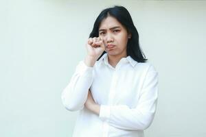 crying asian business woman secretary wipe her tears with hands looking at camera showing sad gloommy expression wearing white shirt formal suit and folding arms standing over isolated background photo