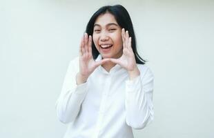 charming beauty cheerful asian business woman shouting at camera with laugh and raised palms announce promotion and new product wearing white shirt formal suit standing isolated background photo