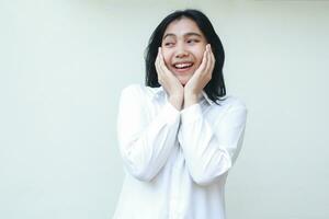 portrait of amazed asian business woman smiling excited and leaning face on hands looking away wearing white shirt formal suit standing isolated background photo