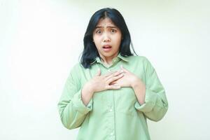 shocked dark hair asian woman wearing green oversized shirt touching chest and looking at camera stunned and feeling guilty, showing disbelief expression isolated on white background photo