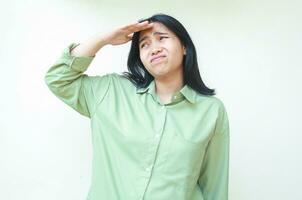 depressed asian woman with dark hair looking away with raising palms over forehead wearing green oversize shirt showing afraid expression isolated on white background photo