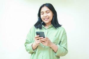 happy asian woman wearing green casual shirt smiling while using smartphone apps and social media isolated on white background photo