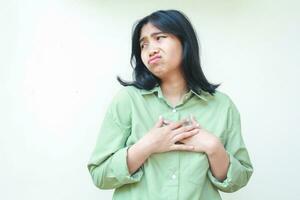 sad asian woman with dark hair wearing green shirt looking aside to empty space with worry face expression have overthinking and anxiety, standing over isolated white background photo