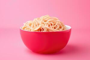 Bright color changing noodles in bowl isolated on a pink gradient background photo