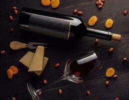 vaso y botella de rojo vino con queso, seco albaricoques y nueces foto