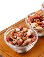Assorted nuts in a glass bowls on wooden photo