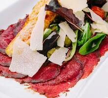 Beef carpaccio with salad and Parmesan on a white plate photo