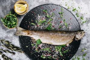 Grilled spicy fish on black plate, top view photo