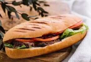 Sandwich with meat and vegetables on a wooden board photo