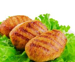 Three cutlets with lettuce close up isolated photo