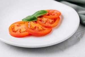 Sliced red tomatoes and basil leaves photo