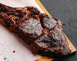 Freshly grilled Tomahawk steak on wooden cutting board photo