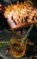 Whiskey in a glass with ice and a chessboard photo