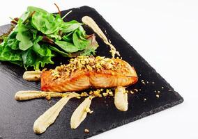 Grilled salmon fish fillet with crushed pistachios with green salad photo