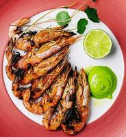 grilled tiger prawns or shrimps on red plate photo