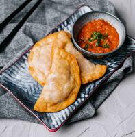 Homemade chebureks with filling and salsa sauce photo