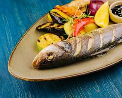 Seabass baked with grilled vegetables on plate photo