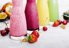 Four different smoothies of berry, banana with tangerine, kiwi, strawberries photo