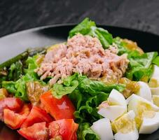 Tuna and vegetable salad on black plate photo