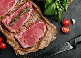 Raw strip loin steaks on baking paper photo