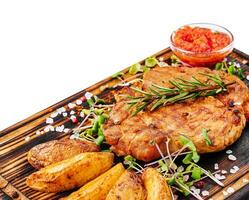 Grilled steak with baked potatoes on wood photo