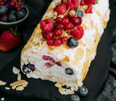 Meringue roll with cream and berries and almonds photo